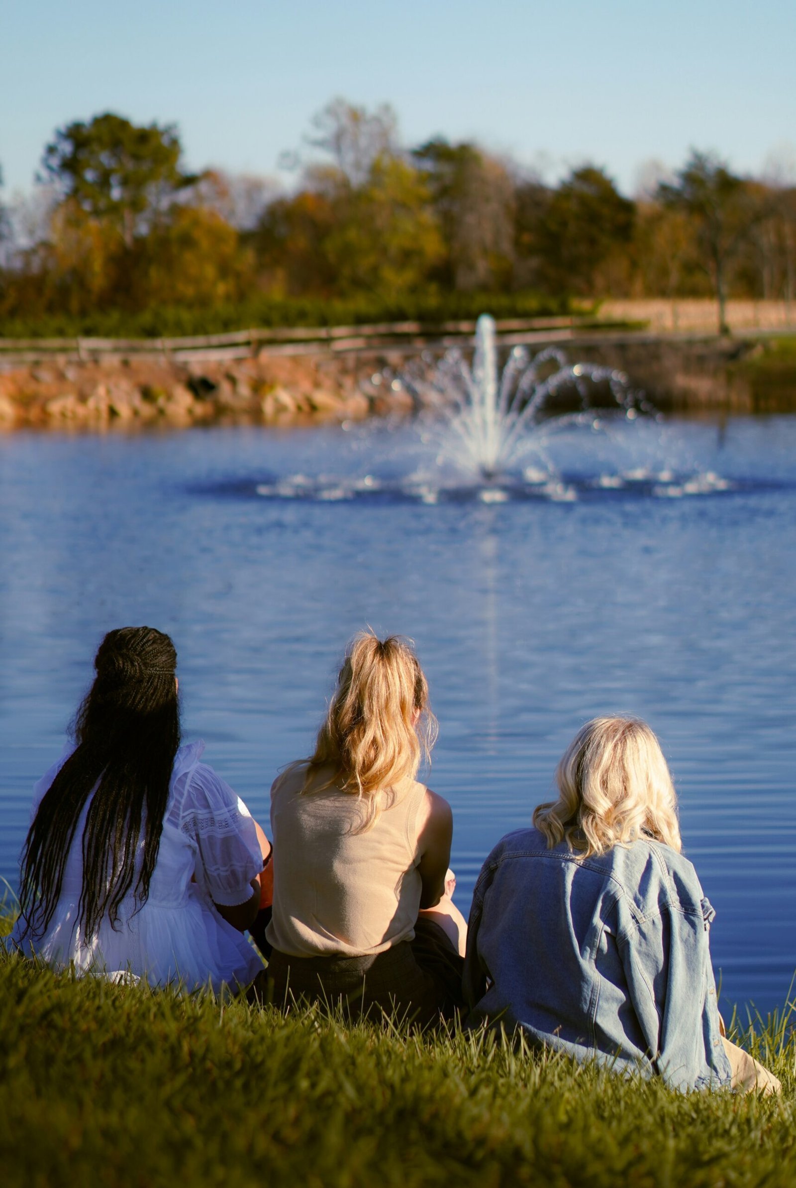 A group of people sitting on the grass near a lake